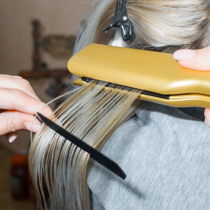 Keratin hair straightening with a professional iron. Hairdresser performing hair treatment. Spa salon concept, hairdressing Keratin hair straightening with a professional iron. Hairdresser performing hair treatment. Spa salon concept, hairdressing